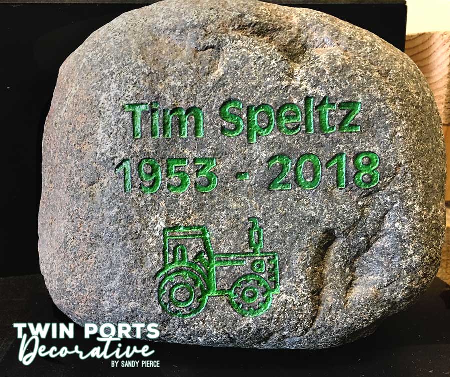 Rock sandblasted to say name and years with tractor art.